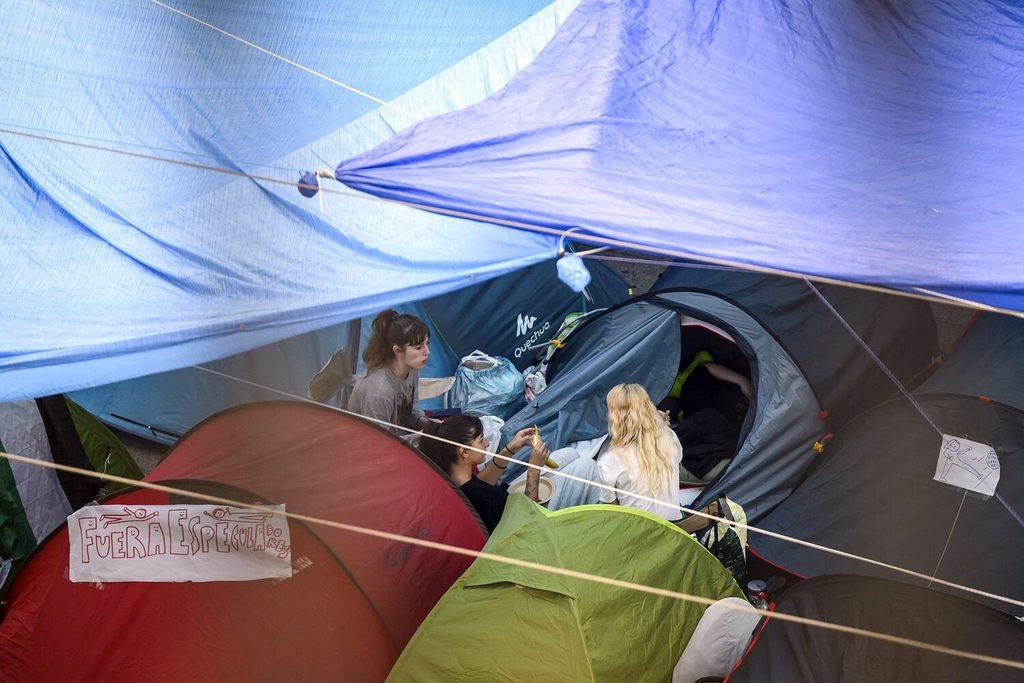 Tres personas hablan en sus tiendas de campañas en la acampada por la vivienda en Sol. Álvaro Minguito.