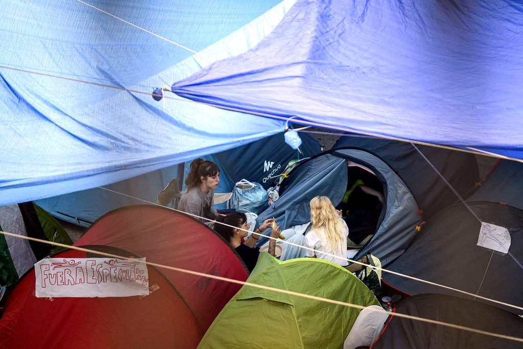 Tres personas hablan en sus tiendas de campañas en la acampada por la vivienda en Sol. Álvaro Minguito.