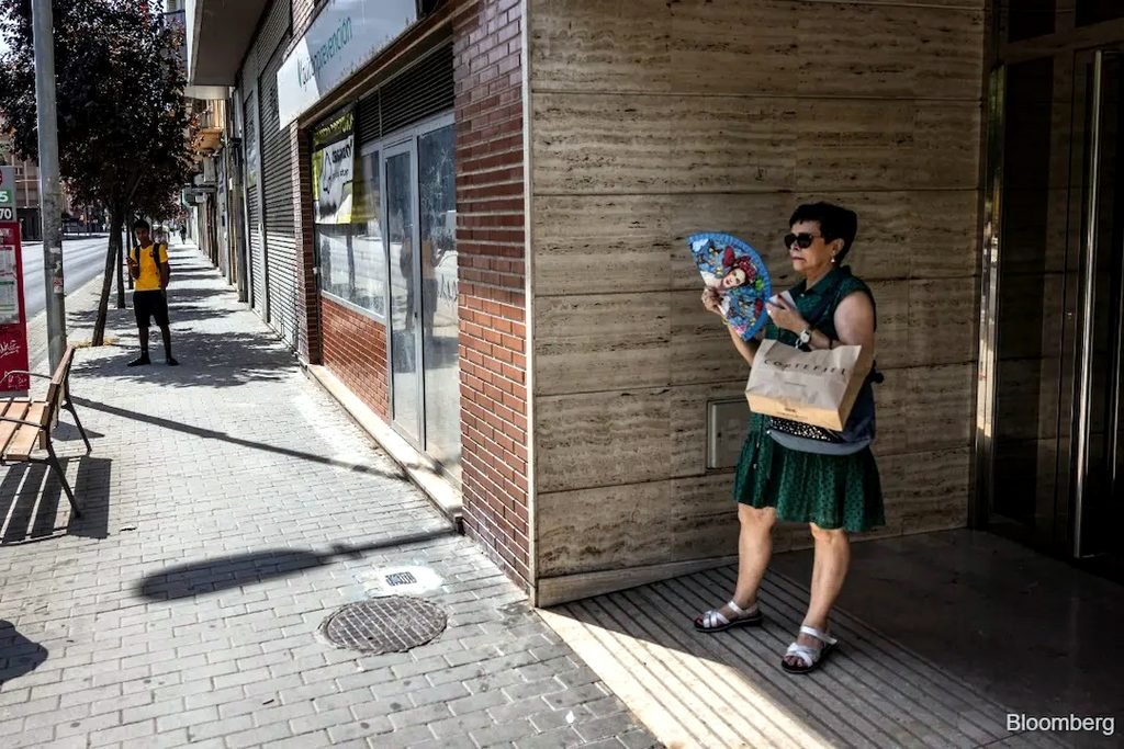 Una mujer paseando se refresca con un ventilador a la sombra durante una ola de calor en Lleida, España, el 13 de julio.