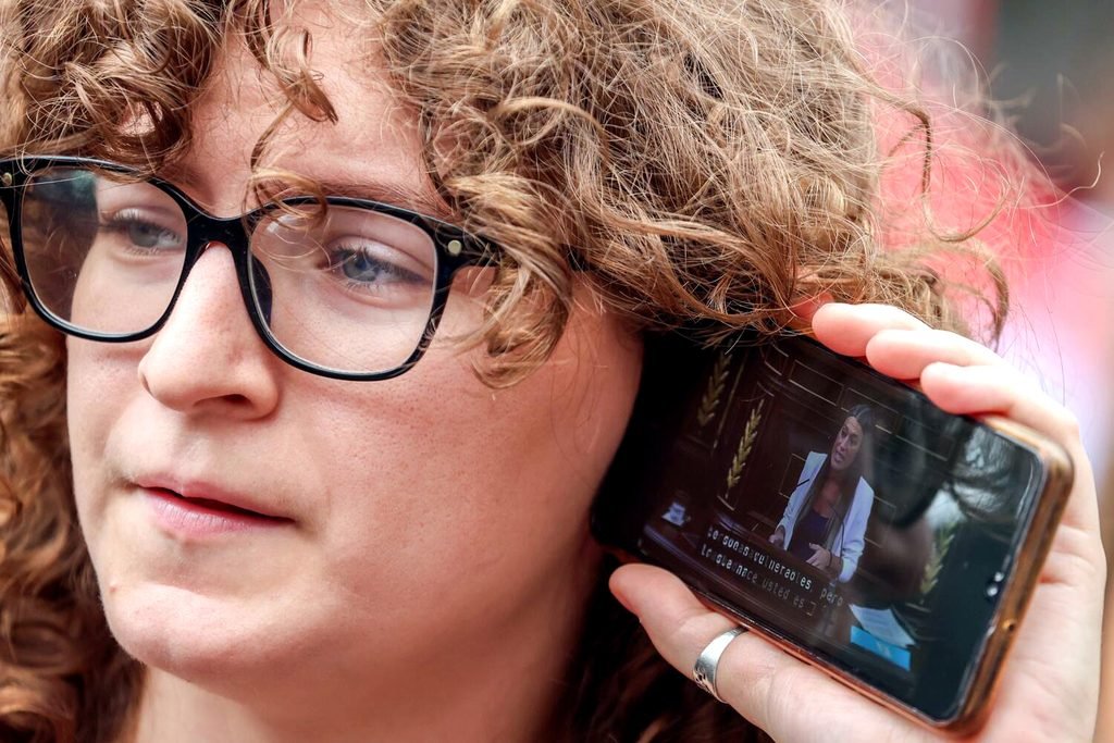 Una joven sigue con su móvil el debate sobre los decretos de vivienda, afuera del Congreso.